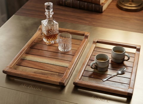 Wooden trays with cups, a decanter, and books on a wooden surface.